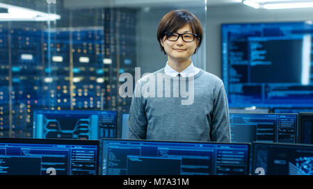 In the System Control Room Technical Operator Stands and Looks at the Camera. He's Surrounded by Multiple Displays Showing Graphics. IT Technician Stock Photo
