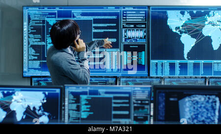 In the System Control Room IT Administrator Talks on the Phone. He's in a High-Tech Facility That Works on the Surveillance, Neural Networks, Data Stock Photo