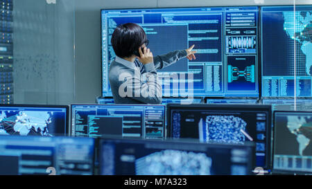 In the System Control Room IT Administrator Talks on the Phone. He's in a High-Tech Facility That Works on the Surveillance, Neural Networks Stock Photo
