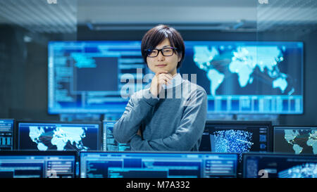 In the System Control Room Smart Engineer Turns and Makes Thinking Gesture. High-Tech Facility Has Multiple Monitors with Graphics. Stock Photo