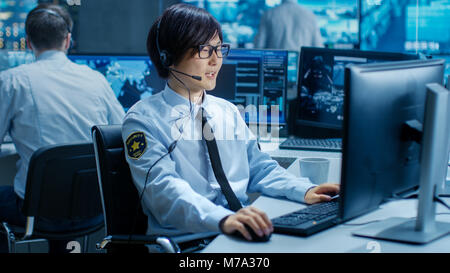 In the Security Command Center Officer at His Workstation Monitors Screens and Communicates with Patrols through Headset. He is Part of Surveillance. Stock Photo