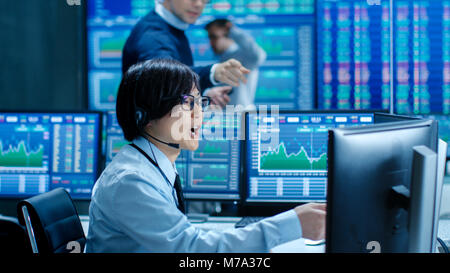In the Network Operations Senior Trader Dictates Stock Numbers to Their Operator who Makes Call with a Headset. In the Background Traders Discuss Data Stock Photo