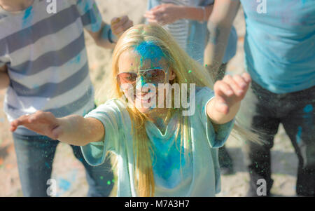 High Angle Shot of Blonde Girl Throwing Colorful Powder in the Crowd Amidst Hindu Holi Festival Celebrations. They Have Enormous Fun on this Sunny Day Stock Photo