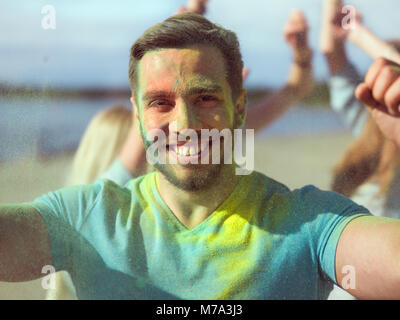 Selfie Portrait of a Muscular Man Celebrating of Holi Festival With His Friends. His Face and Clothes are Covered with Colorful Powder. Stock Photo