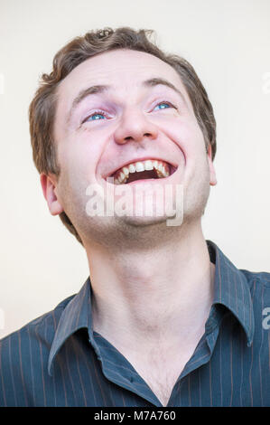 Portrait of young positive smiling curly blue-eyed man on white background. Stock Photo
