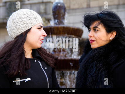 Two female students, Parisian-Algerian Faiza Faa (right) with her Iraqi friend Samar Munaf (left) sitting together at the City fountain in Dundee, UK Stock Photo