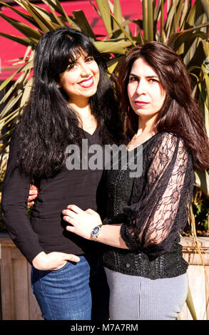 Two female University students, Parisian-Algerian Faiza Faa (left) and friend Samar Munaf from Iraq (right) standing hugging each other in Dundee, UK Stock Photo