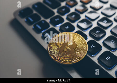 Bitcoin gold coin on computer keyboard backlit Stock Photo