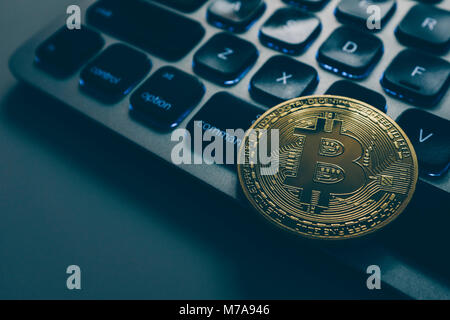Bitcoin gold coin on computer keyboard backlit Stock Photo