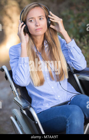 young woman in a wheelchair listening to music Stock Photo