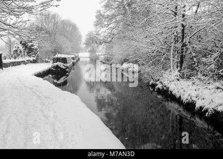 Narrowboats covered in snow are seen moored up on the Llangollen Canal Stock Photo