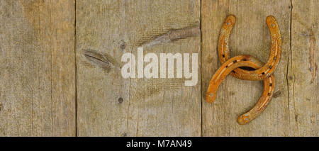 Two old rusty horseshoes hang on wooden wall Stock Photo