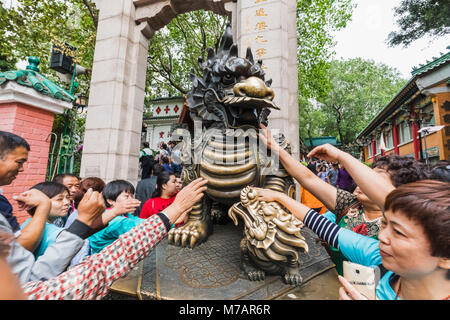 China, Hong Kong, Kowloon, Wong Sai Tin Temple, Chinese Tourists Touching Dragon Statue for Good Luck Stock Photo