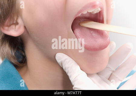 Doctor examining a boy's mouth with a tongue depressor Stock Photo