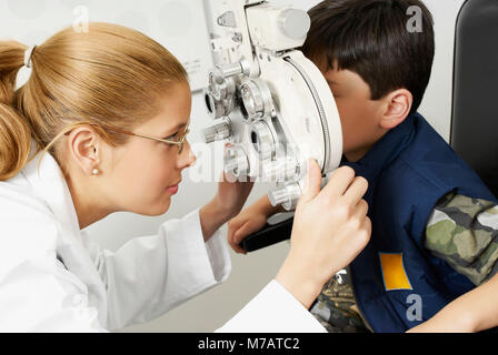 Side profile of a female optometrist examining a boy's eye Stock Photo