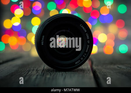 Close-up of the Canon EF 35 mm 1:2 IS USM lens with bokeh Christmas lights in the background Stock Photo