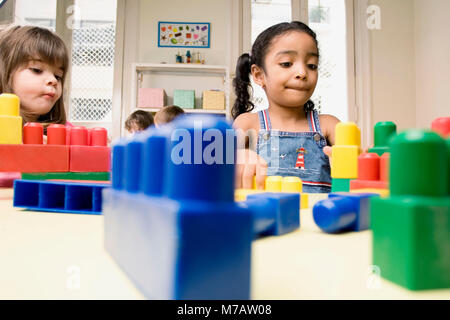 Two girls playing with plastic blocks Stock Photo