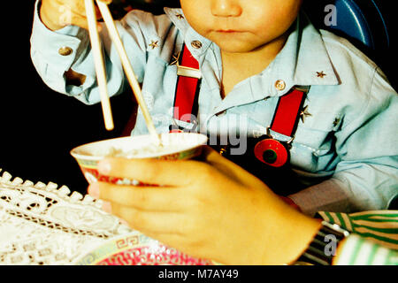 Close-up of a boy learning from his father how to use chopsticks, Hong Kong, China Stock Photo