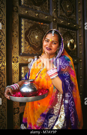 Portrait of a mid adult woman standing in front of a door and greeting, Jaipur, Rajasthan, India Stock Photo