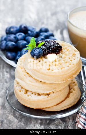 Hot  toasted crumpets on the wooden table with blueberries and jam Stock Photo