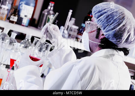 Close-up of a mid adult man stirring liquid in a beaker Stock Photo