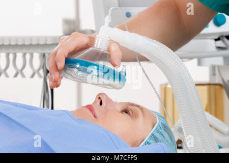 Anesthetist using an oxygen mask on a patient in a hospital Stock Photo