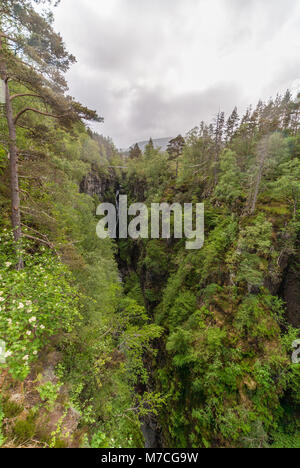 Braemore, Scotland - June 8, 2012: Long view. Corrieshalloch Gorge, a deep cut in landscape with forested vertical slopes. Suspension bridge over chas Stock Photo
