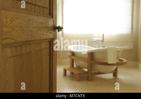 beautiful white bath for an open door. Bath stands in a wooden frame Stock Photo