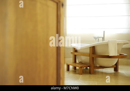 beautiful white bath for an open door. Bath stands in a wooden frame Stock Photo