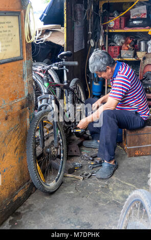 A bike mechanic doing some mechanical maintenance work on a rental mountain bike on the island of Pulau Ubin, Singapore. Stock Photo