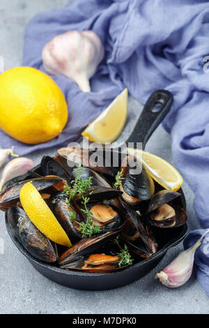 Delicious mussels in shells in lemon-garlic dressing with thyme. Seafood with spices. Appetizer gourmet. Selective focus Stock Photo