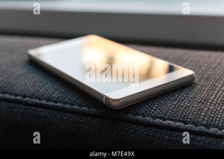 Business Smartphone With Reflection Lying On The Armrest Of A Couch Stock Photo