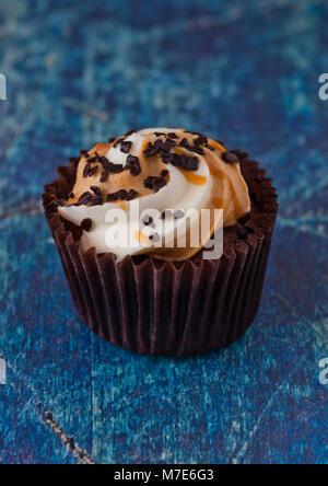 Fresh toffee cupcake muffin with caramel and chocolate on blue wooden background Stock Photo