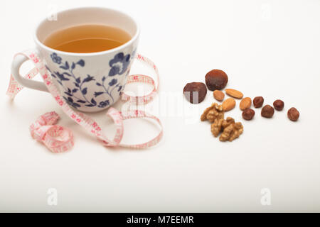 Assorted dried healthy nuts with black tea and a tape measure in a concept of weight loss through correct diet and nutrition Stock Photo