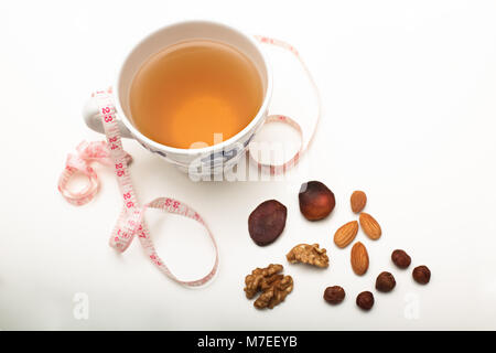 Assorted dried healthy nuts with black tea and a tape measure in a concept of weight loss through correct diet and nutrition Stock Photo
