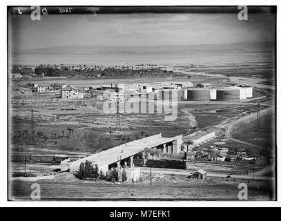 The image depicts 'Shell' oil tanks near Haifa, with a bridge spanning across a railroad track. This photograph captures the industrial landscape and transportation infrastructure in the area. Stock Photo