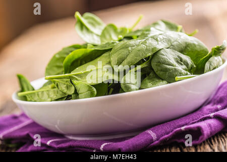 Spinach. Fresh baby spinach leaves in plate on woden table. Stock Photo