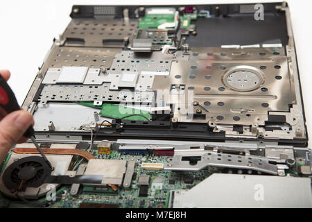 Man working on an opened laptop with the electronics exposed using a small precision screwdriver in a repairs, DIY, servicing and maintenance concept Stock Photo