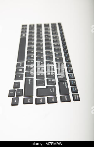 End on receding oblique angle view of a computer keyboard with black keys and shallow dof with foreground copy space on white Stock Photo
