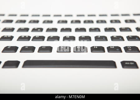 Low angle view of a qwerty alphanumeric computer keyboard with black keys on silver gradient to white with selective focus to the part of center keys Stock Photo