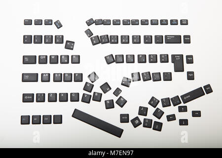 Loose alphanumeric covers for the keys on a laptop computer keyboard scattered randomly on a white surface viewed high angle with foreground copy spac Stock Photo