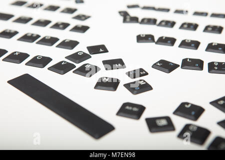 Loose alphanumeric covers for the keys on a laptop computer keyboard scattered randomly on a white surface viewed low  angle with foreground copy spac Stock Photo