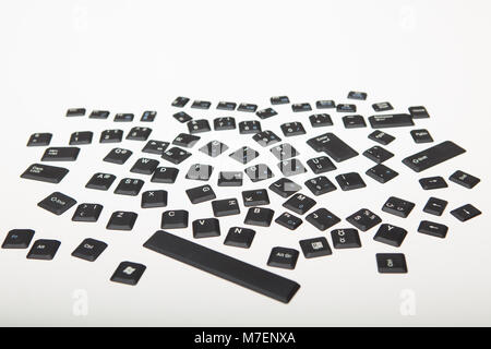 Loose alphanumeric covers for the keys on a computer keyboard in a random jumble on a white or light silver background viewed from low angle Stock Photo