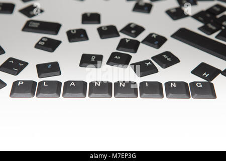 Loose scattered alphanumeric and function key covers from a laptop computer keyboard with the word Planning and digits in a close up high angle concep Stock Photo