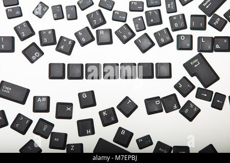 Loose scattered alphanumeric and function key covers from a laptop computer keyboard with a line of blank keys viewed from above Stock Photo