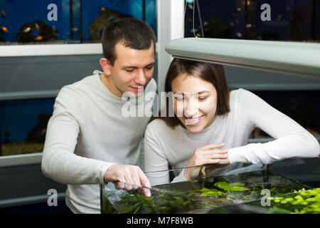 Positive man with happy young girlfriend choosing aquarium fish in aquarium Stock Photo