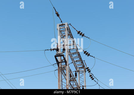 Train or railway power line support. Railway power lines with high voltage electricity on metal poles against blue sky. Stock Photo