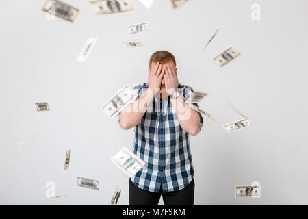 young handsome happy man with red beard standing under money rain of dollar bills Stock Photo
