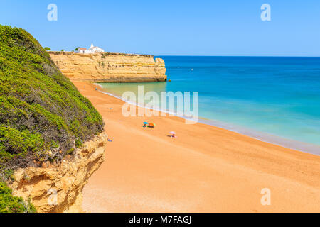 View of beach with rock cliffs and white church in Armacao de Pera town, Algarve, Portugal Stock Photo