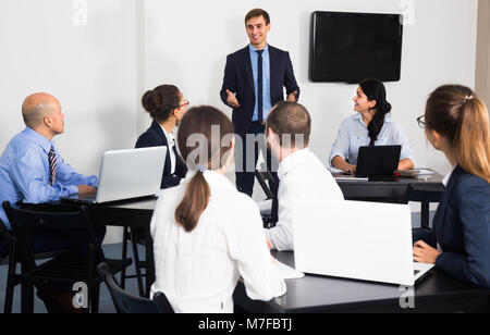 caucasian employee presenting his idea on project to team in office Stock Photo